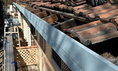 New separate fascia and Colorbond gutter being installed along a tiled roof edge in place of a Nu-Line system